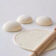 Romana Tonda pizza dough balls with one rolled out thin, showing the characteristic thin Roman-style base