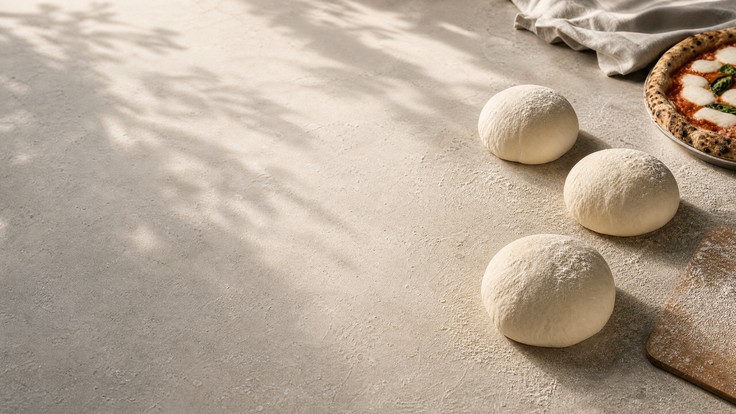 Fresh pizza dough and a Neapolitan pizza on a flour-dusted work surface