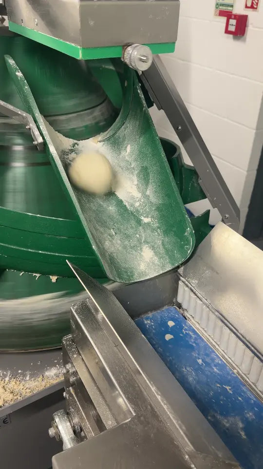 Rounded dough portions moving onto a conveyor