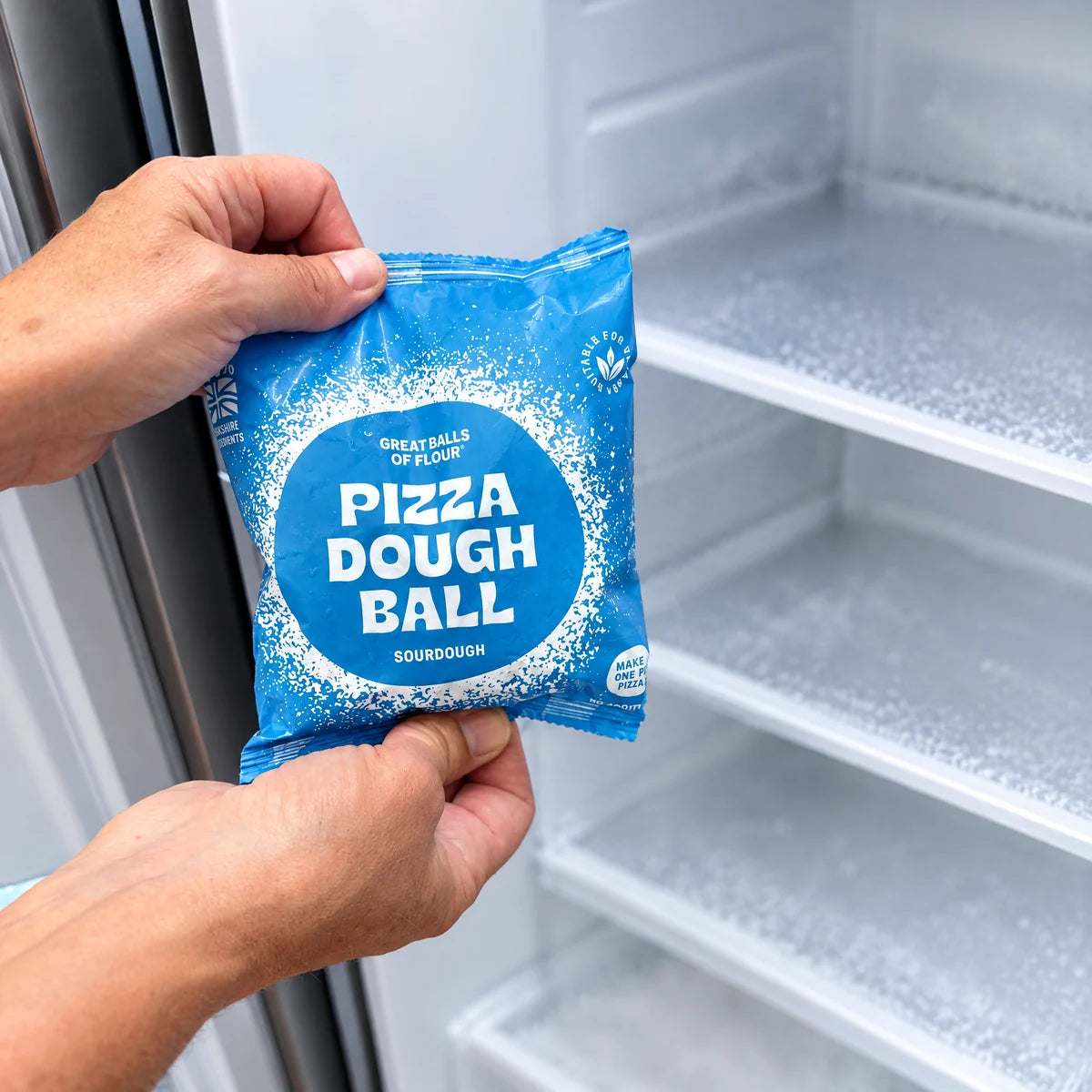 Sourdough pizza dough pack held in front of a freezer